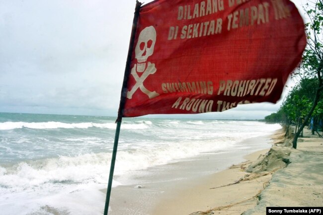 Bendera peringatan berkibar saat gelombang tinggi mencapai pantai di Kuta, Bali, 2 Maret 2006. (Foto: AFP/Sonny Tumbelaka)