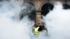 Para demonstran mengenakan rompi kuning berjalan melewati bom asap dekat taman-taman Tuileries di Paris, Sabtu, 22 Desember 2018. (Foto: AP/Kamil Zihnioglu)