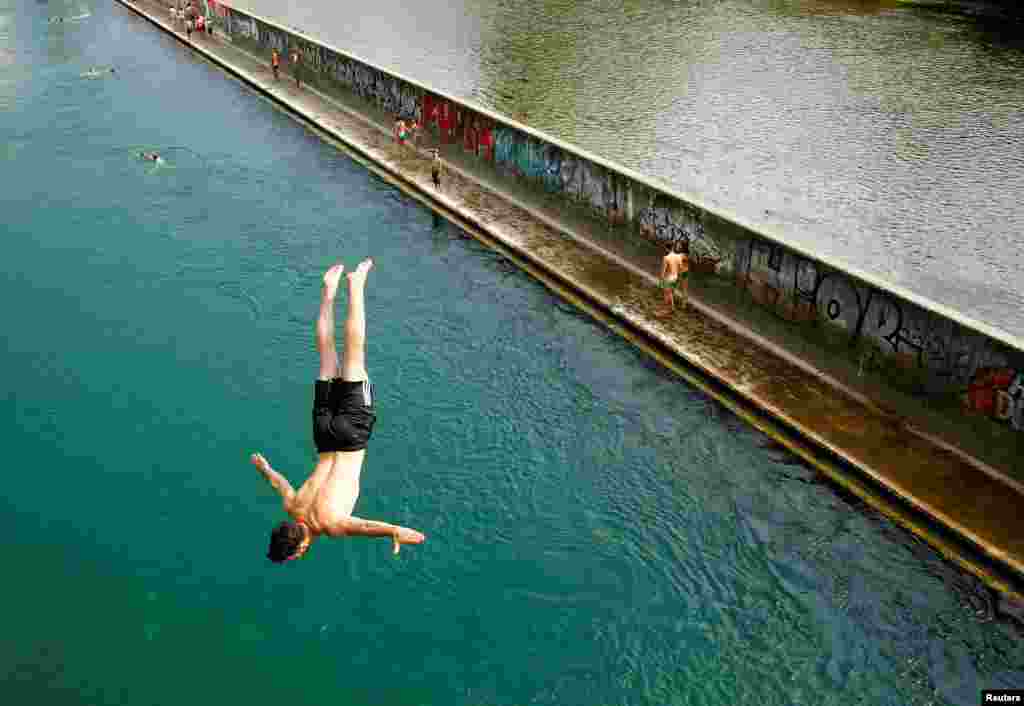 A man jumps from a bridge into the Limmat river during hot temperatures in Zurich, Switzerland.