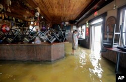 Un hombre de pie en medio de las aguas de la inundación en Don'z On the Lake mientras los vientos de la tormenta tropical Barry empujan el agua sobre el dique del lago Pontchartrain el sábado 13 de julio de 2019. (David Grunfeld / The Advocate vía AP)