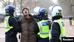 လန်ဒန်မြို့မှာ COVID-19 အရေး အသွားအလာ ကန့်သတ်တားမြစ်ချက်တွေ ဆန့်ကျင်ဆန္ဒပြသူတဦးကို ဖမ်းဆီးနေတဲ့ ရဲတပ်ဖွဲ့ဝင်များ။ (နိုဝင်ဘာ ၂၈၊ ၂၀၂၀)