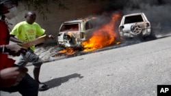 People run after cars were set on fire near a Best Western hotel during protests over a fuel price increase in Port-au-Prince, Haiti, July 7, 2018.