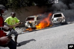People run after cars were set on fire near a Best Western hotel during protests over a fuel price increase in Port-au-Prince, Haiti, July 7, 2018.