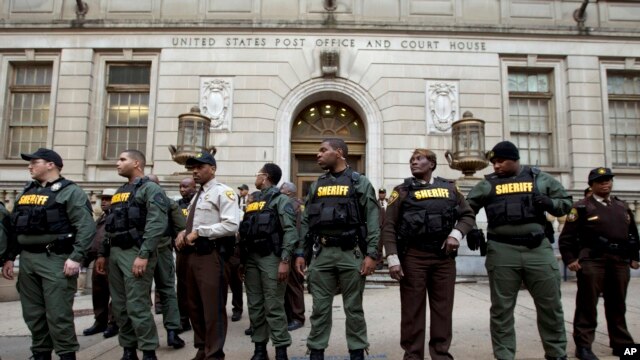 Agentes de la Oficina del Alguacil en Baltimore resguardan la entrada principal de la Corte de Circuito de la ciudad mientras manifestantes protestaban la nulidad del juicio contra el primero de seis policías acusados en conexión con la muerte del detenido estadounidense Freddie Gray.