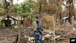 Seorang polisi berdiri di antara puing-puing permukiman warga etnis Muslim Rohingya yang habis dibakar dalam kerusuhan (foto: dok).