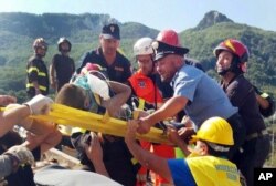 FILE - Firefighters and rescuers pull out a boy, Mattias, from the collapsed building in Casamicciola, on the island of Ischia, near Naples, Italy, a day after a 4.0-magnitude quake hit the Italian resort island, Aug. 22, 2017.