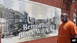 Freeman Culver stands in front of a mural listing the names of businesses destroyed during the Tulsa race massacre in Tulsa, Okla., Monday, June 15, 2020. (AP Photo/Sue Ogrocki)