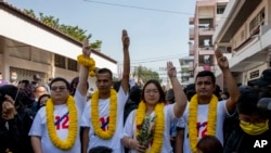 Pro-democracy movement protest leaders from left, Parit Chiwarak, Panupong Jadnok, Panusaya Sithijirawattanakul and Shinawat Chankrajang flash three-finger salute as they walk to appear in a police station in Northaburi, Thailand, Tuesday, Dec. 8, 2020. Four leaders report to ack