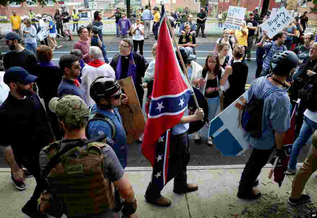 A white supremacists carries the Confederate flag as he walks past counter demonstrators in Charlottesville, Virginia, Aug. 12, 2017. 