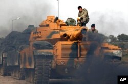 FILE - Turkish Army soldiers prepare their tank at a staging area in the outskirts of the village of Sugedigi, Turkey, on the border with Syria, Jan. 22, 2018.