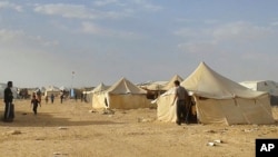 FILE - Syrians walk through the Ruqban refugee camp in Jordan's northeast border with Syria on June 22, 2016. Jordanian authorities announced Tuesday, Nov. 22, 2016, the resumption of aid to thousands of people, half of them children, who have been stuck with little food, water, medical care and other necessities since Jordan closed the border on June 21, 2016, to Syrian refugees. 