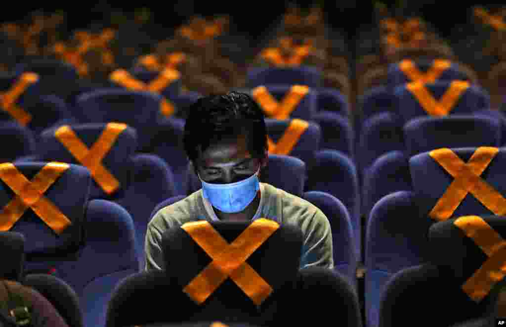 A man checks his mobile phone as he sits amid physical distancing markers prior to the start of a movie at CGV Cinemas theater in Jakarta, Indonesia.