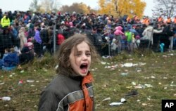 FILE - A girl cries as hundreds of migrants wait to cross into Austria from Sentilj, Slovenia, Oct. 29, 2015.