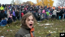 A girl cries as migrants wait to cross into Austria from Sentilj, Slovenia, Oct. 29, 2015. In the migration chaos, children are especially vulnerable to predators. In Germany, a suspect in the death of one boy has confessed to a second slaying, prosecutors say.