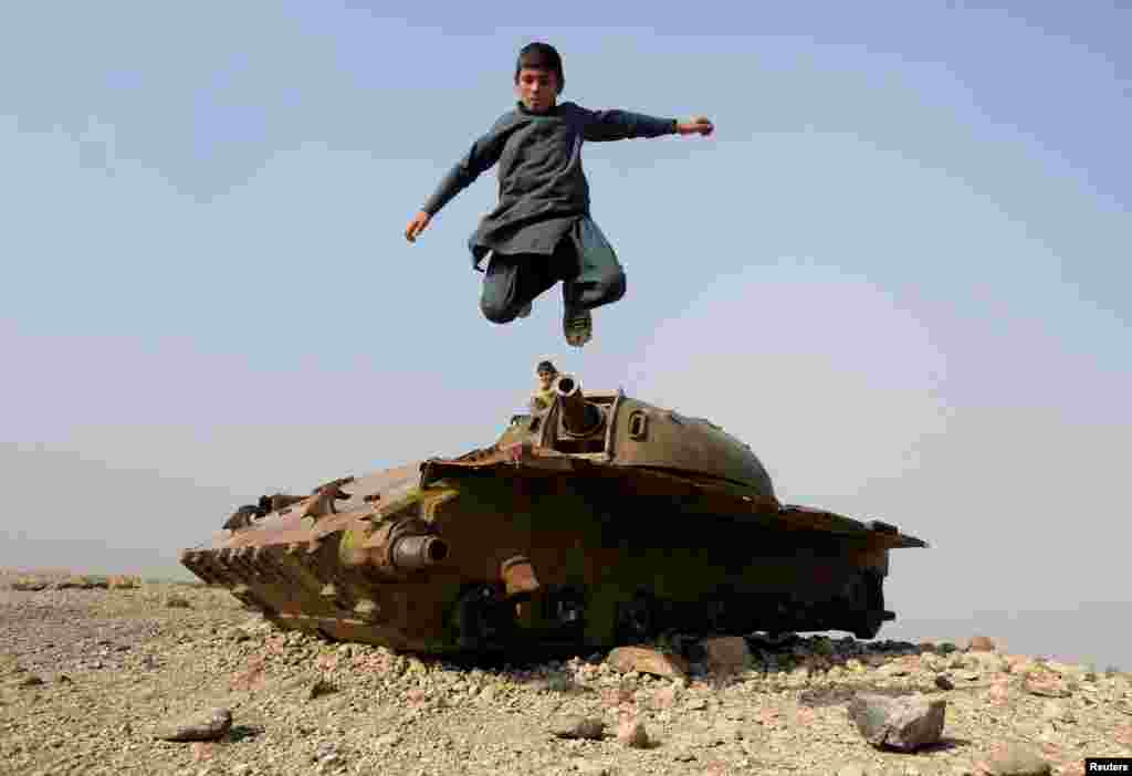 An Afghan boy jumps from the remains of a Soviet-era tank on the outskirts of Jalalabad, Afghanistan.
