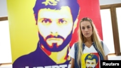 FILE - Lilian Tintori, wife of jailed Venezuelan opposition leader Leopoldo Lopez, stands near a poster depicting him at the Popular Will party's office in Caracas, Venezuela, Jan. 18, 2017.