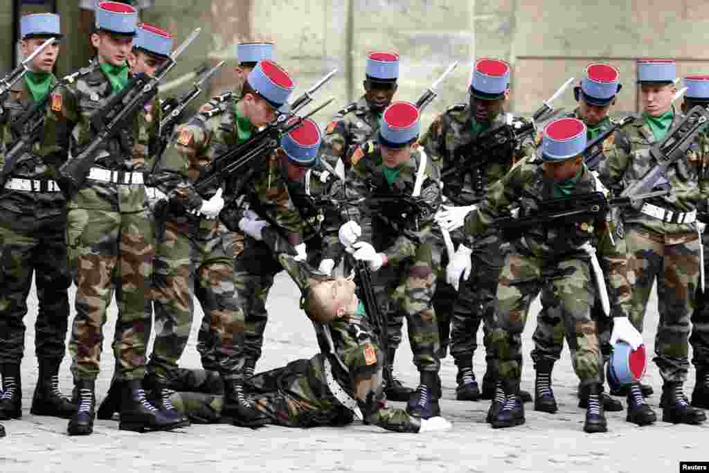 Tentara Perancis membantu sesama prajurit yang jatuh pingsan saat upacara untuk menghormati almarhum mantan Perdana Menteri Perancis Pierre Mauroy di halaman Invalides, Paris.