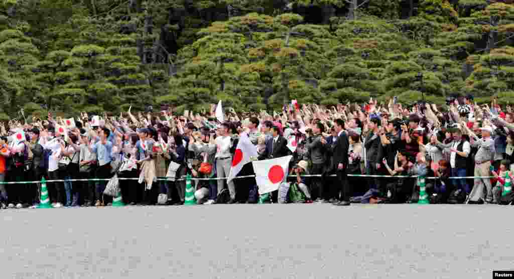 People wave Japanese flags and take pictures of Emperor Naruhito as he leaves the Imperial Palace in Tokyo.