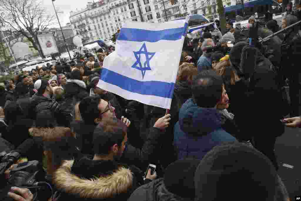 A man waves an Israeli flag in support of Israel's Prime Minister Benjamin Netanyahu's visit at the kosher supermarket in Paris where four hostages were killed on Friday in Paris, France, Jan. 12, 2015.