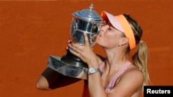 Maria Sharapova of Russia kisses the trophy as she poses during the ceremony after defeating Simona Halep of Romania during their women's singles final match to win the French Open tennis tournament at the Roland Garros stadium in Paris June 7, 2014.