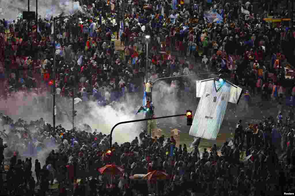 Argentina's fans run away from tear gas as they clash with riot police in Buenos Aires after Argentina lost to Germany in their 2014 World Cup final soccer match in Brazil, July 13, 2014.