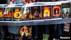 A child gestures at the feet of protesters holding a sign commemorating victims of self-immolation during a solidarity march to the United Nations Headquarters in support of Tibet, New York, December 10, 2012.
