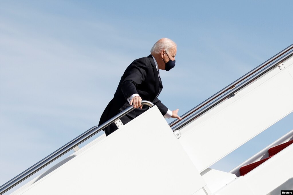 拜登总统在登上“空军一号”专机前往佐治亚州时在舷梯上跌倒后扶住栏杆。(2021年3月19日)(photo:VOA)