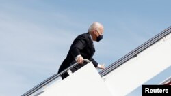 Tổng thống Mỹ Joe Biden nắm lấy tay vịn cầu thang sau khi ông vấp ngã trong khi leo lên chuyên cơ Air Force One rời Washington bay tới Atlanta, bang Georgia, tại Căn cứ Liên hợp Andrews, bang Maryland, ngày 19 tháng 3, 2021.