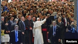 Pope Francis waves to gathered worshipers as he leaves St. Patrick's Cathedral after presiding over an evening prayer service, in New York, September 24, 2015.