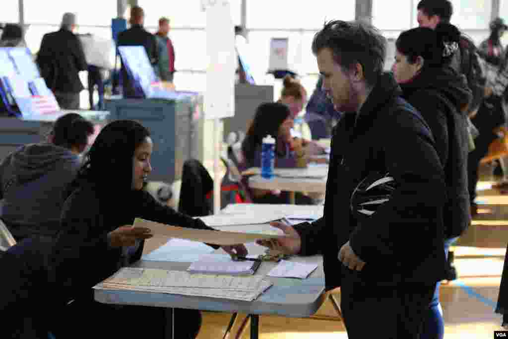 Warga mendapatkan kertas suara sebelum memilih di sebuah TPS di kota New York (8/11). (VOA/R. Taylor)