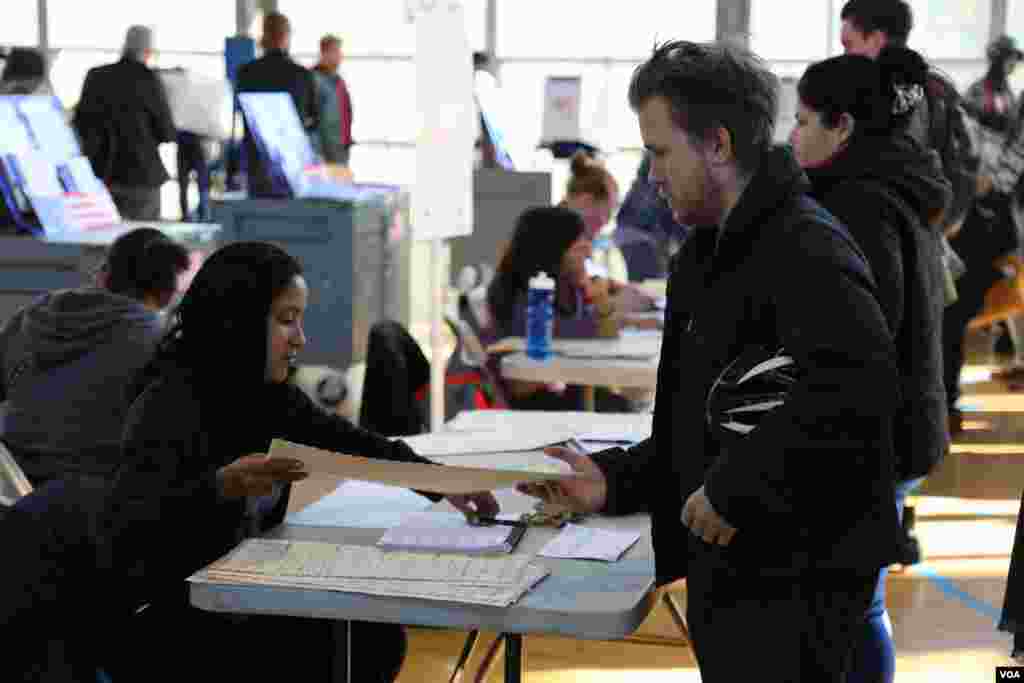 Voter gets his ballot before voting in presidential election at polling station in New York City, Nov. 8, 2016. (Photo: R. Taylor / VOA)