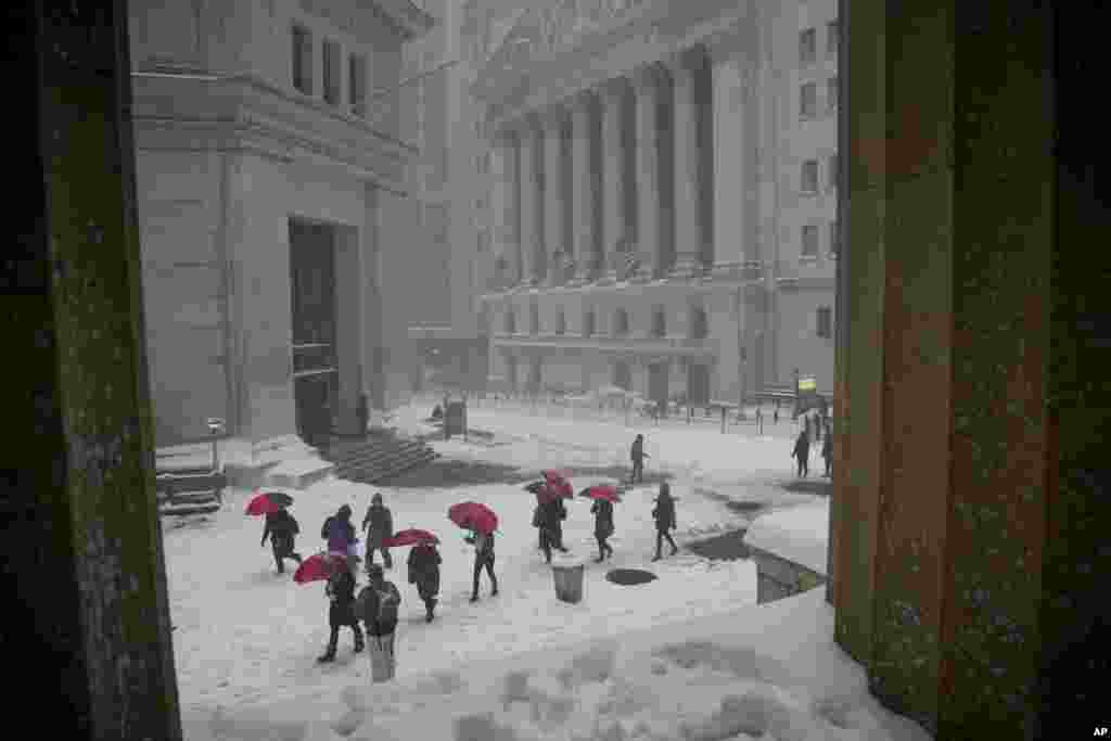 A group of travel advisors from across the country pass the New York Stock Exchange while touring lower Manhattan during a snowstorm, Saturday, Jan. 23, 2016, in New York. (AP Photo/Julie Jacobson)