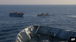 FILE - In this photo released by the Italian Navy Wednesday, April 9, 2014, Italian Navy's dingies approach a boat carrying migrants along the Mediterranean sea, off the Sicilian island of Lampedusa