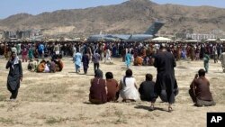 In this Aug. 16, 2021, file photo hundreds of people gather near a U.S. Air Force C-17 transport plane along the perimeter at the international airport in Kabul, Afghanistan. (AP Photo/Shekib Rahmani, File)