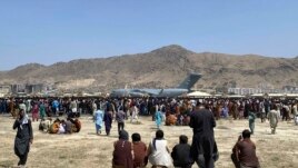 In this Aug. 16, 2021, file photo hundreds of people gather near a U.S. Air Force C-17 transport plane along the perimeter at the international airport in Kabul, Afghanistan. (AP Photo/Shekib Rahmani, File)