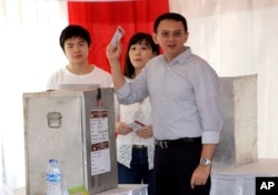 FILE - Jakarta Governor Basuki "Ahok" Tjahaja Purnama who is seeking for his second term in office, his wife Veronica and son Nicholas, left, cast their ballot at a polling station during the runoff election in Jakarta, Indonesia, April 19, 2017.
