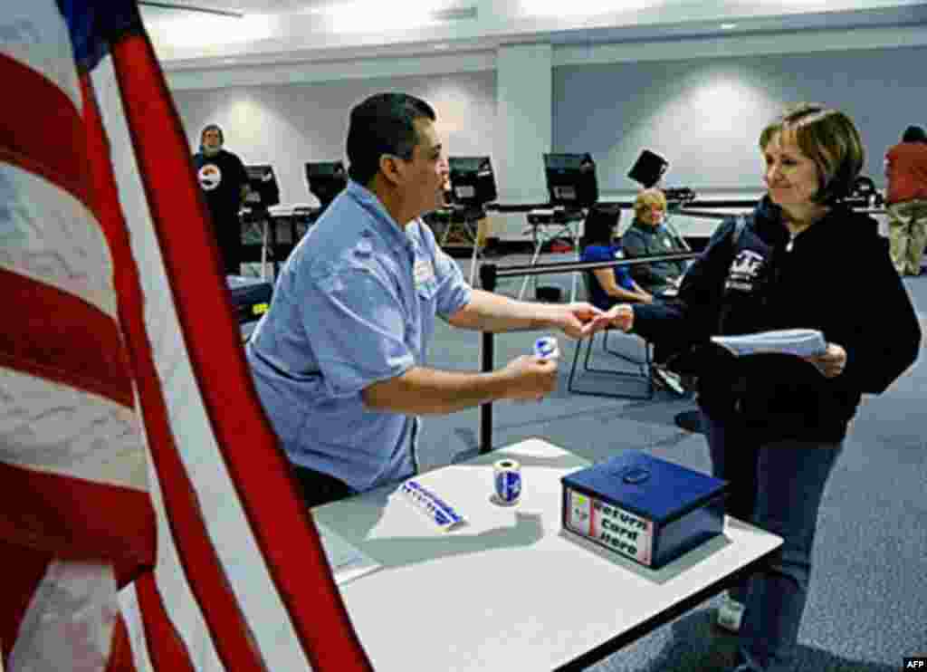 Polling place assistant Salvador Cabrera (L) gives an "I Voted" sticker to Debbie Cluff after she cast her vote at the Sahara West Library in Las Vegas, Nevada, 02 Nov 2010 