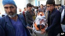 Petugas medis mengangkut korban luka-luka dalam ledakan bom kuat di Kabul hari Sabtu (23/7). 
