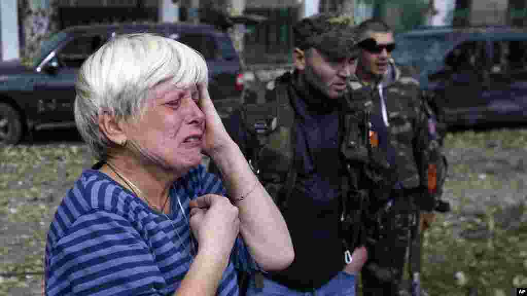 A local woman cries in front of a damaged school after shelling in the town of Donetsk, eastern Ukraine, Oct. 1, 2014. 