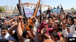 Thanh niên Iraq nâng vũ khí và hô khẩu hiệu ủng hộ lời kêu gọi của giáo sĩ Ayatollah Ali al-Sistani, ở thành phố thánh địa Najaf, 14/6/2014.