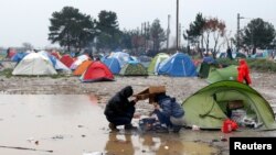 在希腊与马其顿边界的一个临时搭建的难民营里，移民试图在雨中做饭。（2016年3月9日）