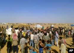 FILE - People gather for a food aid distribution at Rukban refugee camp on the Jordan-Syria border, Aug. 4, 2016. The camp is home to some 50,000 Syrians.