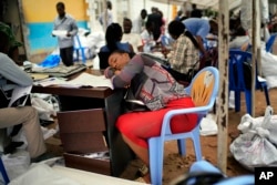 An exhausted Congolese independent electoral commission (CENI) official rests as results are tallied for the presidential election, at a local results compilation center in Kinshasa, Congo, Jan. 6, 2019.