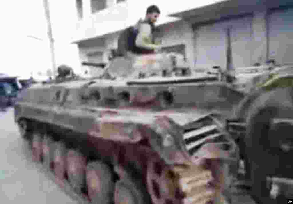 This image from amateur video and released by Shaam News Network purports to show a Syrian rebel atop of a Syrian military tank in Khan Sheikhoun, Syria, March 13, 2012. (AP/Shaam)