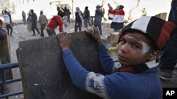 An Egyptian boy takes cover while others throw stones during clashes with the security forces near the interior Ministry in downtown Cairo, Egypt, February 3, 2012.
