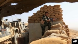 An Iraqi Kurdish peshmerga fighter stands guard outside Bartella, Iraq, Oct. 21, 2016. The historically Christian town is located some 15 kilometers (9 miles) from Mosul's outskirts.