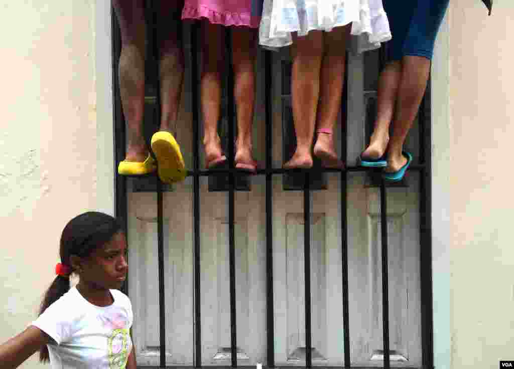 Cuban girls strain to see near a cathedral in Old Havana, Cuba. (R. Taylor / VOA) 