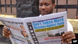 A man reads a newspaper with headlines reading 'Gov't Takes More Measures Against Ebola, as fear about the virus spread in the city of Monrovia, Liberia, July 31, 2014.