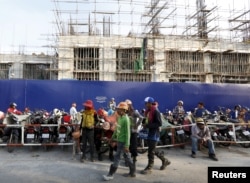 FILE - Laborers rest in front of a construction site of the HongKong Land in Phnom Penh, Cambodia, Oct. 19, 2015. High-rise apartments are springing up across Cambodia's capital, part of a property boom led by expat demand, while developers are also betting on the middle class.