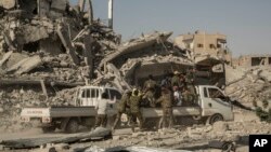 FILE - Members of the U.S.-backed Syrian Democratic Forces (SDF) ride near near the main traffic circle in Raqqa, Syria, Oct. 20, 2017. 